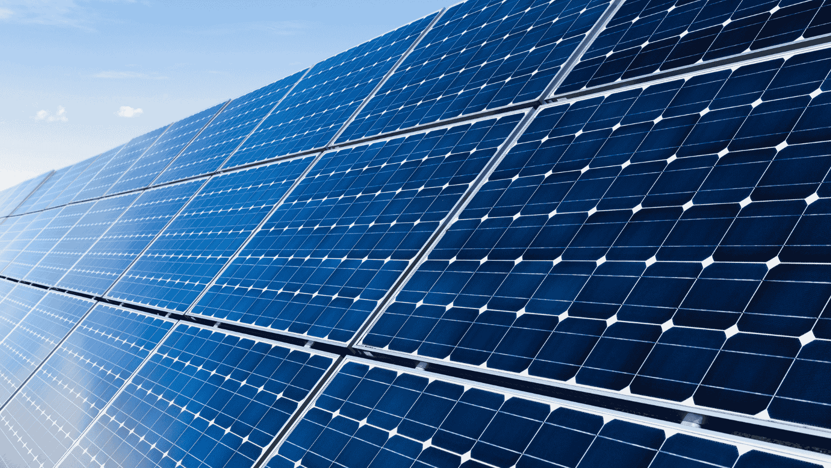 Gros plan sur des rangées de panneaux photovoltaïques sous un ciel bleu